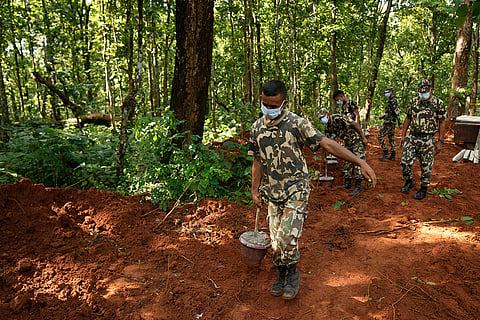 Nepal's paramilitary force personnel carry numbered identification tags in pots to mark the graves of flash flood victims at a mass burial site in Chitwan, Nepal.