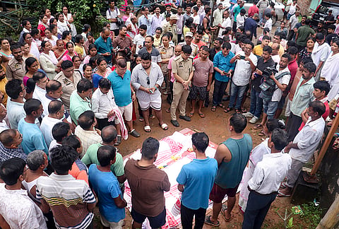 People gather near the mortal remains after three members of a family died in a landslide triggered by incessant rainfall, while another sustained injuries, at Mathgharia area, in Guwahati, Assam. The landslide occurred while the family was sleeping at home. 