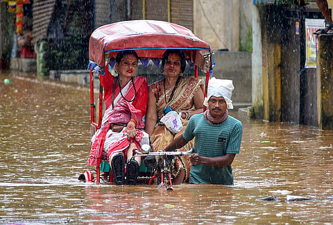 A rickshaw puller wades through a waterlogged road after rain, in Guwahati.