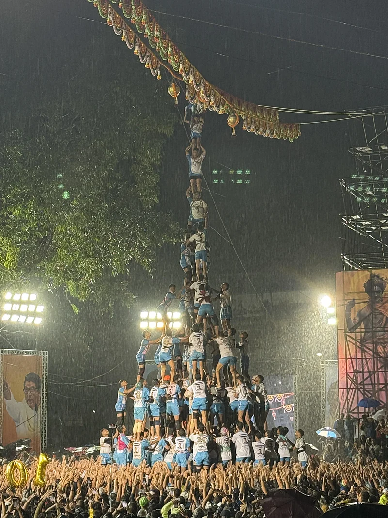 A large team of people building a high human pyramid
