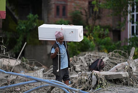 A resident carries an air cooler salvaged from his damaged house after flash flooding in the Devighat area of Nuwakot district, Nepal, Saturday, Aug. 29, 2026.