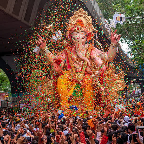 Lord Ganesha idol surrounded by devotees during Ganesh Chaturthi celebrations.
