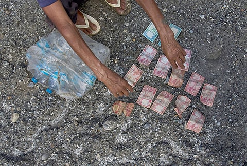 A man salvages a money and bottles of mineral water from his house affected by flash floods in Dhading District, Nepal, Sunday, Aug. 30, 2026. 