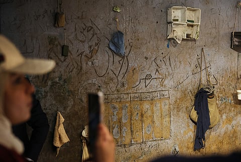 A visitor photographs a display using original items from Military Security Branch 248 to recreate a cell as it appeared during the rule of former President Bashar Assad at "When the Walls Speak," an exhibit at the Damascus International Fair in Damascus, Syria, Monday, Aug. 31, 2026. 