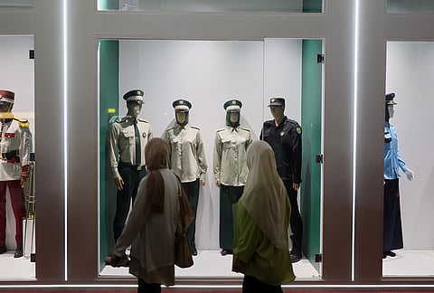 Visitors walk past Syrian police uniforms on display at the 63rd Damascus International Fair on the outskirts of Damascus, Syria, Monday, Aug. 31, 2026. 