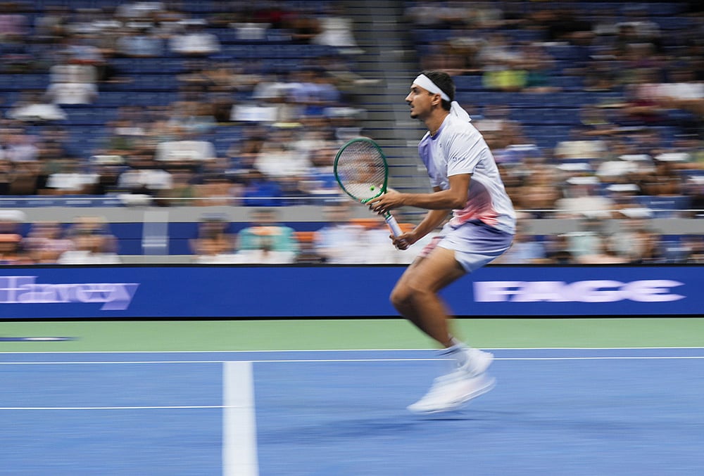 In this image taken with a slow shutter speed, Lorenzo Sonego, of Italy, rushes the net during the fourth set against Alexander Zverev, of Germany, in the first round of the U.S. Open tennis championships early Wednesday, Sept. 2, 2026, in New York. 