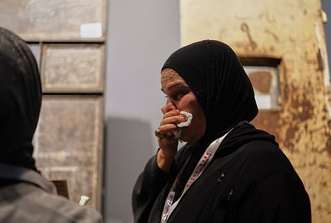 A woman becomes emotional while viewing a display using original items from Syria's Saydnaya prison to recreate a cell as it appeared during the rule of former President Bashar Assad at "When the Walls Speak," an exhibit at the Damascus International Fair in Damascus, Syria, Monday, Aug. 31, 2026. 
