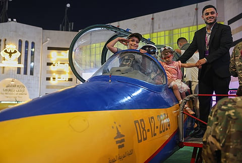 A boy salutes from the cockpit of an aircraft on display at the 63rd Damascus International Fair in Damascus, Syria, Monday, Aug. 31, 2026. 