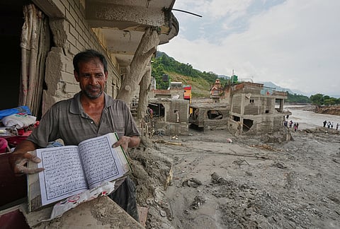 A resident shows a holy book as he salvages his belongings from damaged home filled with mud and debris in Devighat, in Nepal's Nuwakot district, Saturday, Aug. 29, 2026, following the Aug. 26 flash floods. 