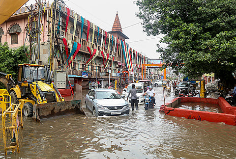 Commuters wade through a waterlogged road following rainfall, in Mathura, Uttar Pradesh.