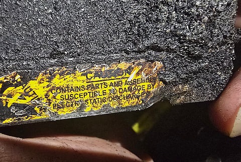 A person holds a fragment of a projectile bearing a warning in English at a site that Iranian media said was hit in a U.S. strike in Kuhestak, southern Iran, early Wednesday, Sept. 2, 2026. 