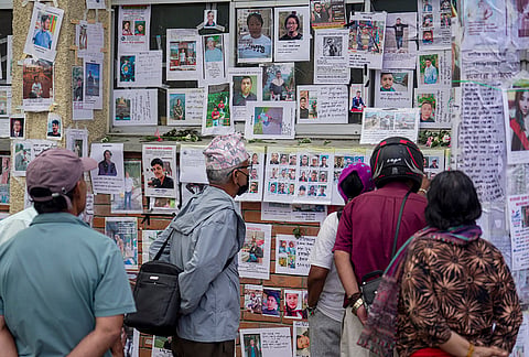 Family members look at the details of the people who went missing after the flash floods, outside Tribhuvan University in Kathmandu, Nepal.