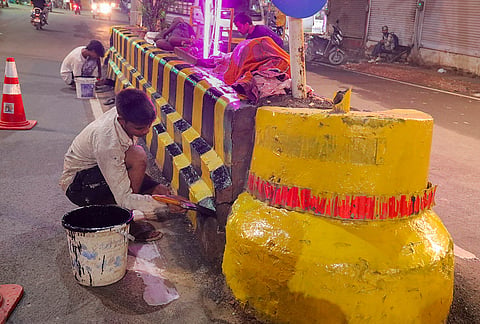 Workers paint road dividers ahead of UP CM Yogi Adityanath’s visit for the 'Janmashtami' festival celebrations, in Mathura.