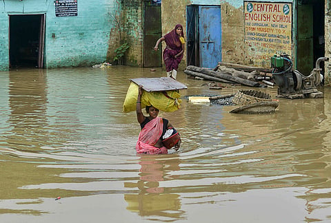 A woman carrying her belongings wade through a waterlogged area after the swollen Ganga river inundates low-lying areas, at Bind Toli, in Patna, Bihar, Thurssday, Sept. 3, 2026. 