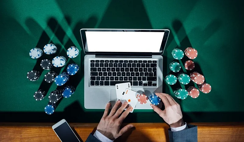 Laptop open to a poker game on green felt with chips