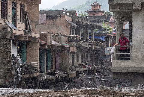 A resident stands on the balcony of a damaged building during heavy rainfall along the Trishuli River, at Devighat, in Nuwakot district, Nepal, Friday, Sept. 4, 2026. The region was struck by devastating flash floods and mudslides following a high-altitude glacier collapse in late August. 