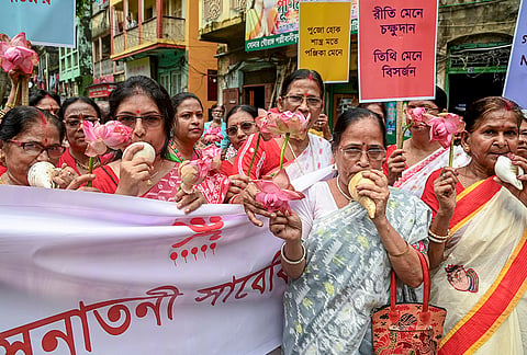 Women blow conch shells and hold lotus flowers as they participate in a procession to demand traditional Durga Puja festival celebrations, in Kolkata.