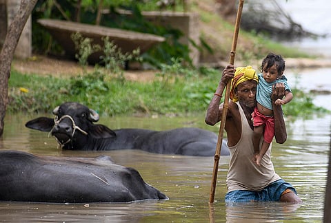 A man with a child wades through floodwaters following a rise in the water level of the Ganga river, at Nakta Diyara, in Patna, Bihar, Saturday, Sept. 5, 2026. 