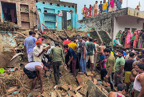 People gather after a house collapsed amid rain at Hirni village, in Kanpur, Uttar Pradesh. Four members of a family were killed and another seriously injured in the incident. 