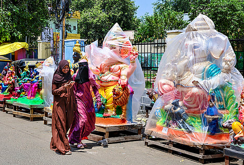 Women walk past idols of lord Ganesh covered in plastic sheets at a roadside workshop ahead of 'Ganesh Chaturthi' festival, in Chennai.