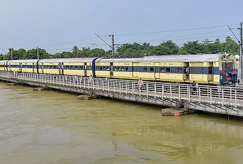 A passenger train crosses a flooded bridge following a rise in the water level of the Punpun river, in Patna, Bihar.