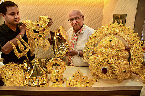 Goldsmith Nana Sanjay Vedak, centre, along with an assistant displays gold ornaments crafted for 'Sarvajanik Ganesh' mandals ahead of the Ganesh Chaturthi festival, in Mumbai.