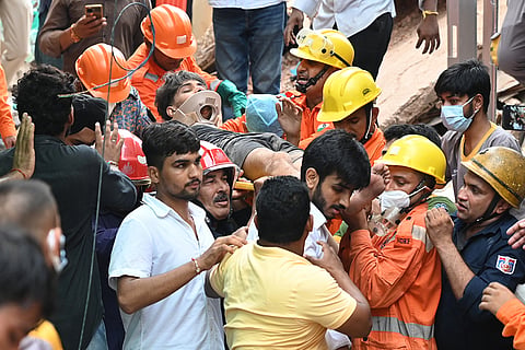 Rescue workers carry a student they have rescued from the debris of a collapsed building in New Delhi, India.