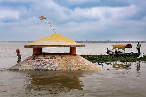 A partially submerged pavilion structure stands in the swollen Ganga river following a rise in water level due to heavy rainfall, at Dashashwamedh Ghat, in Prayagraj.