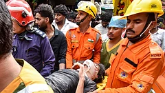 Delhi Building Collapse LIVE: NDRF, fire department officials carry a rescued person after a 50-year-old five-storey building housing a boys' hostel collapsed in a congested bylane in Satya Niketan near Delhi University’s south campus. Three died in the incident. - | Photo: PTI