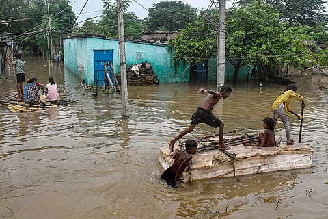Children use makeshift boats to move on an inundated area following the rise in the water level of Ganga river, in Patna.