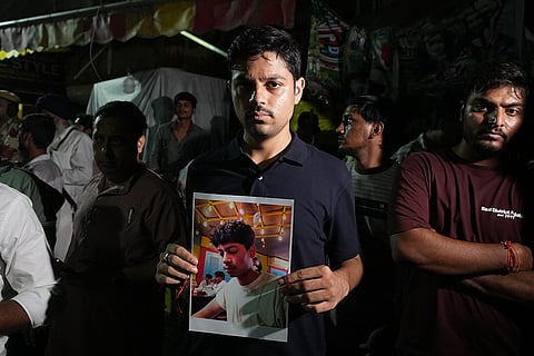A man holds a photograph of his friend, Pawan Kumar, who is missing following a building collapse in New Delhi, India.