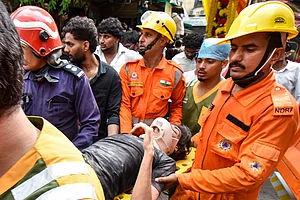 | Photo: PTI : NDRF, fire department officials carry a rescued person after a 50-year-old five-storey building housing a boys' hostel collapsed in a congested bylane in Satya Niketan near Delhi University’s south campus. Three died in the incident.