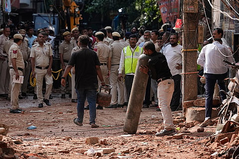 A rescue worker carries a cylinder at the site of a collapsed building in New Delhi, India.