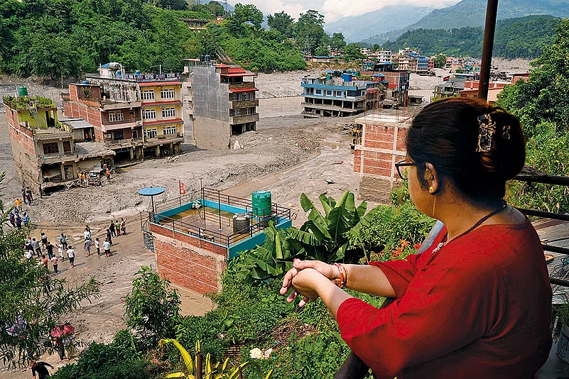 A woman looks at the devastation left by the floods in Dhunge Bazaar, Nepal