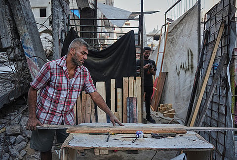Palestinian carpenter Alaa Joudah, 39, cuts wood to use for building a new wooden house next to his home, which was destroyed during the war between Israel and Hamas, in Gaza City, Wednesday, Sept. 2, 2026. 