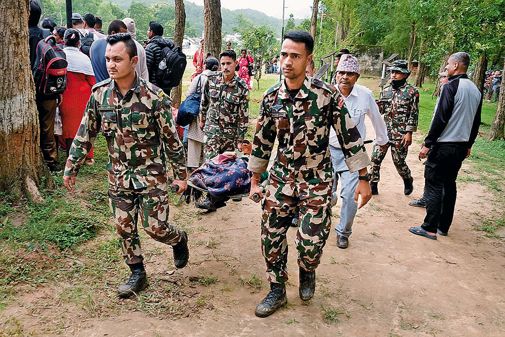 Nepal security personnel carry a rescued elderly woman on a stretcher at the Trishuli Army Camp