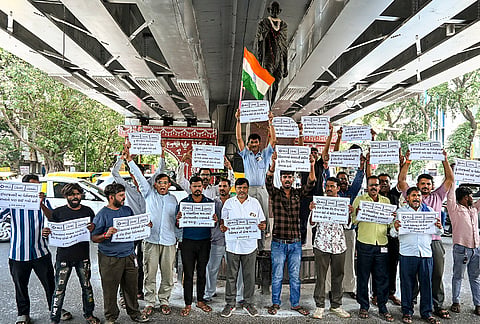 Auto-rickshaw drivers hold placards as they stage a protest against ride-hailing apps like Rapido, Uber and Ola, in Ahmedabad.