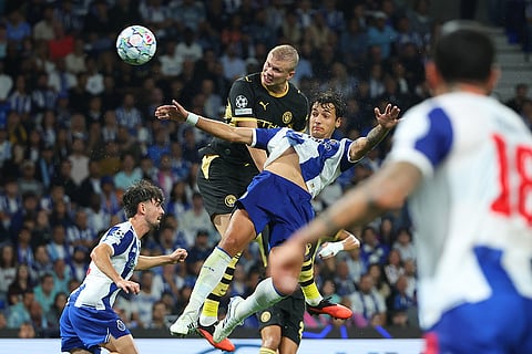 Manchester City's Erling Haaland attempts a header at goal above Porto's Jakub Kiwior during a Champions League opening phase soccer match between FC Porto and Manchester City in Porto, Portugal.