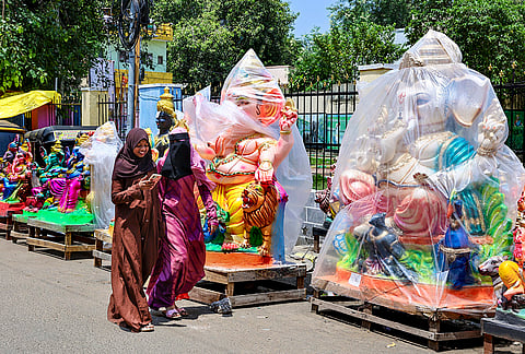 Women walk past idols of lord Ganesh covered in plastic sheets at a roadside workshop ahead of 'Ganesh Chaturthi' festival, in Chennai, Sunday, Sept. 6, 2026. 