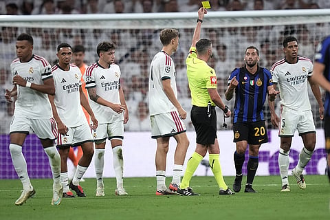 Inter Milan's Hakan Calhanoglu receives a yellow card during a Champions League soccer match between Real Madrid and Inter Milan in Madrid, Spain.