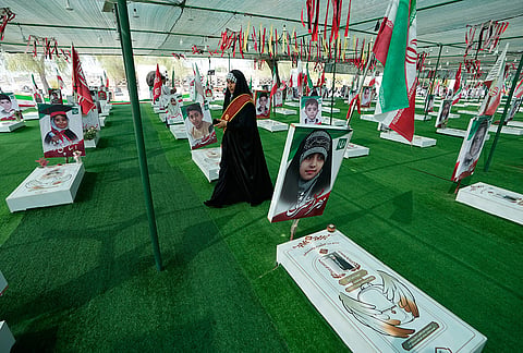 A woman walks at the graveyard of the school children who were killed after their school was a hit by a strike on Feb. 28, in town of Minab in southern Iran, Saturday, Sept. 5, 2026. 