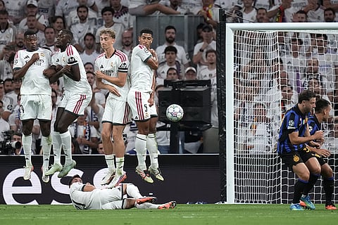 Real Madrid players jump while forming a barrier during a Champions League soccer match between Real Madrid and Inter Milan in Madrid, Spain.