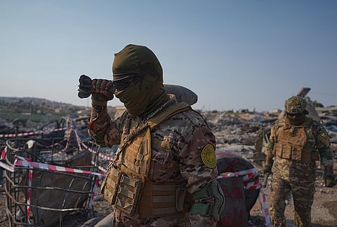 A member of Syria's armed forces holds a damaged rocket-propelled grenade at the site of an explosion at what the Defense Ministry said was a warehouse used to store weapons and munitions near Sarmada, in Idlib province, Syria, Wednesday, Sept. 9, 2026. 