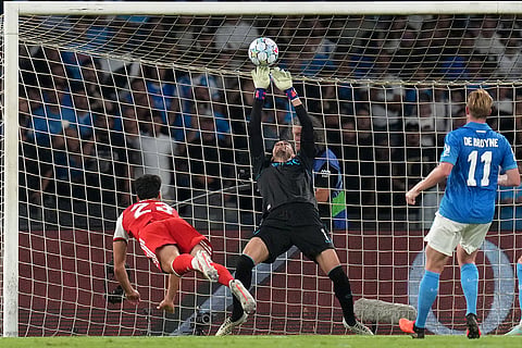 Napoli's goalkeeper Alex Meret, center, makes a save in front of Arsenal's Mikel Merino, left, during their Champions League soccer match between Napoli and Arsenal, in Naples, southern Italy.