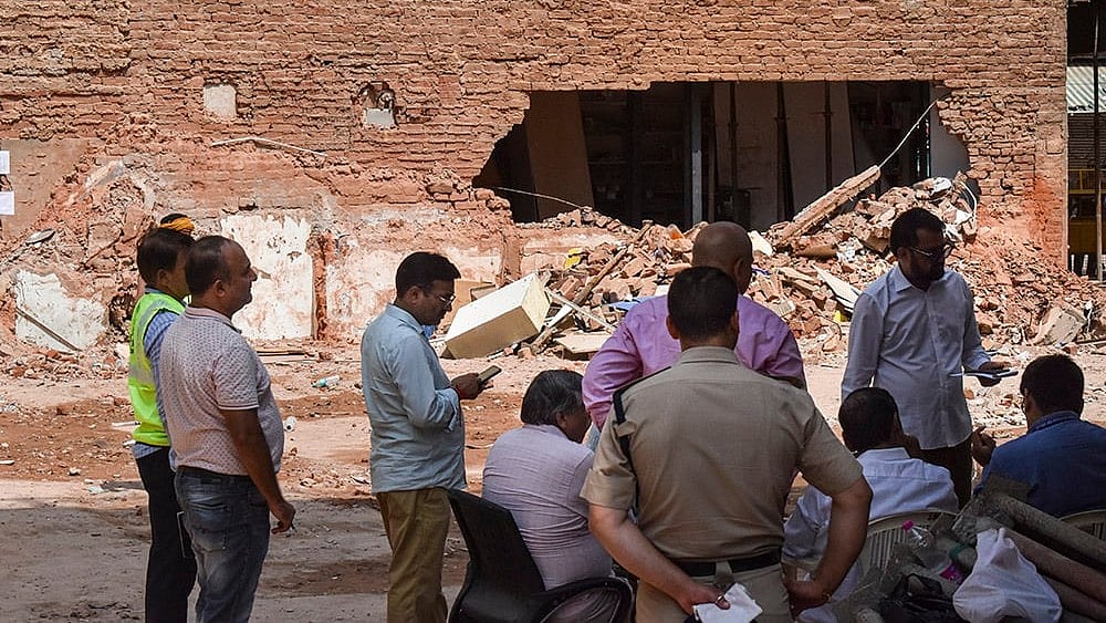 Police officials and people gather at the site during a rescue operation following the collapse of a multi-storey building housing a PG accommodation at Satya Niketan, in New Delhi. Atleast seven people were killed.  - | Photo: PTI/Rushikesh More