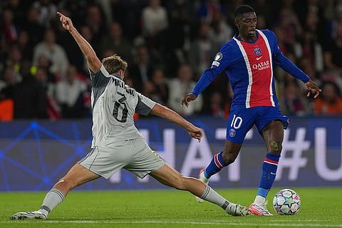 PSG's Ousmane Dembele, right, and Slovan's Peter Pokorny battle for the ball during the Champions League opening phase soccer match between PSG and Slovan Bratislava in Paris.