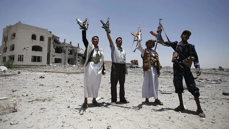 Houthis fighters hold weapons while chanting slogans