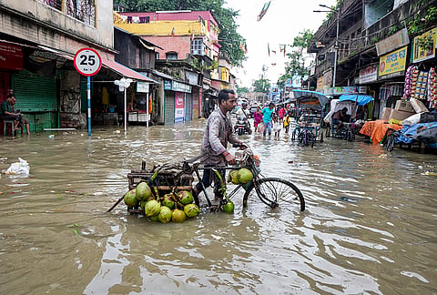 A vendor wades through high tide water of the Ganga river in the Kalighat area, in Kolkata, West Bengal.