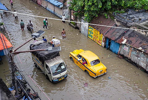 Commuters wade through high tide water of the Ganga river in the Kalighat area, in Kolkata, West Bengal. 