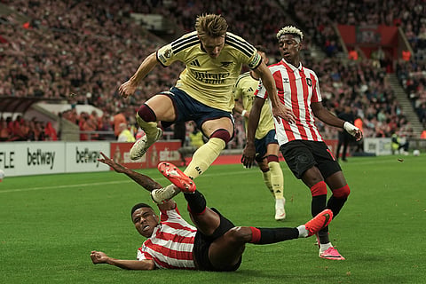 Arsenal's Martin Odegaard, top, and Sunderland's Reinildo Mandava challenge for the ball during the English Premier League soccer match between Sunderland and Arsenal in Sunderland, England.